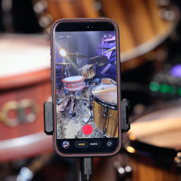 Teléfono móvil en un soporte grabando una batería acústica al fondo.